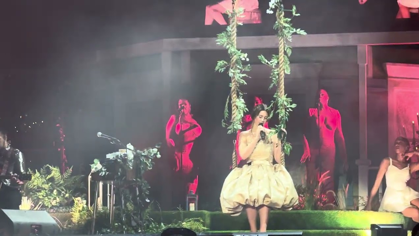 Lana Del Rey sitzt während ihres Auftritts beim Formel-1-Wochenende in Singapur auf einer mit Pflanzen geschmückten Schaukel und singt auf einer aufwendig inszenierten Bühne.